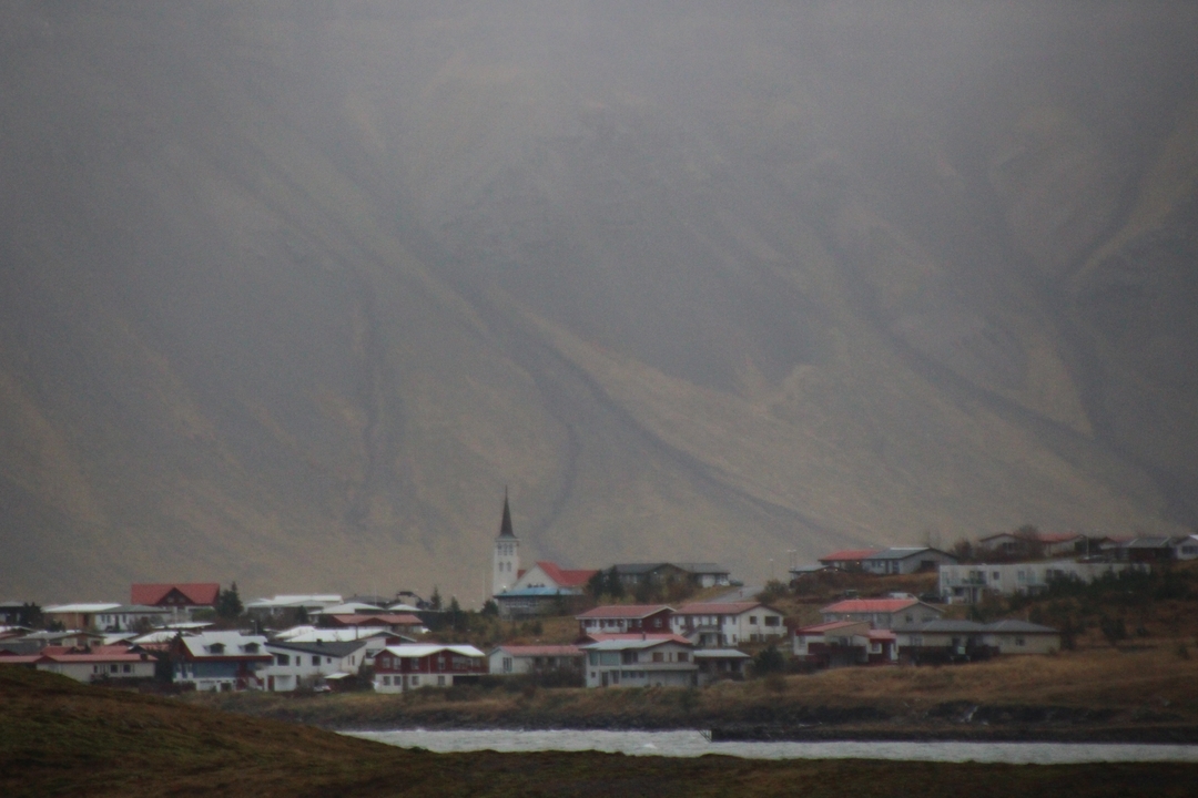Lointain village avec une église sur fond de montagnes.