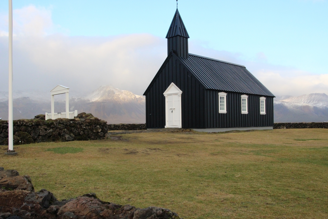 Église noire avec des montagnes à l'arrière-plan.