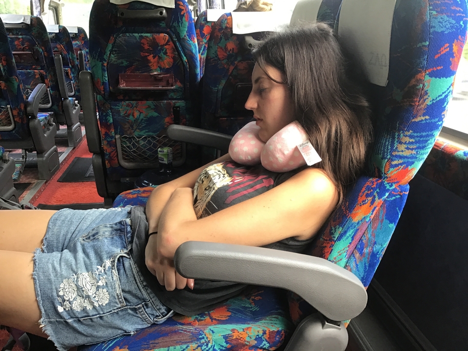 Personne dormant sur un siège de bus coloré.