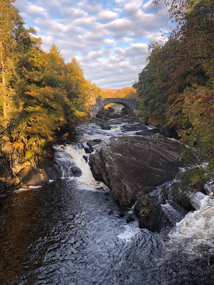 Bridge over a river with cascading waterfalls.