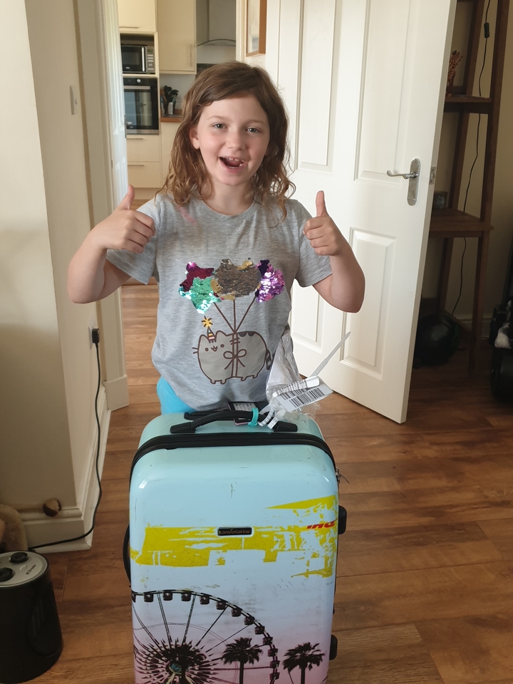 Enfant faisant un pouce levé avec une valise à l'intérieur