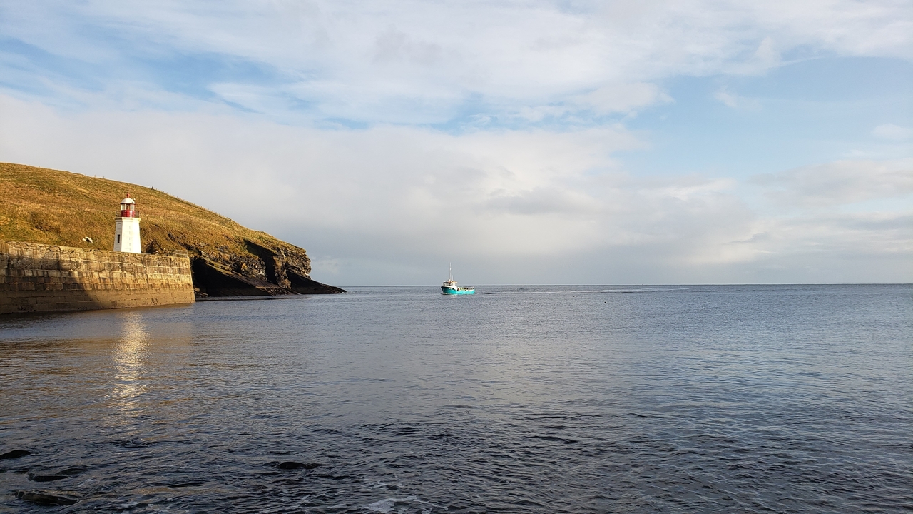 Phare sur un rivage rocheux avec un bateau qui passe