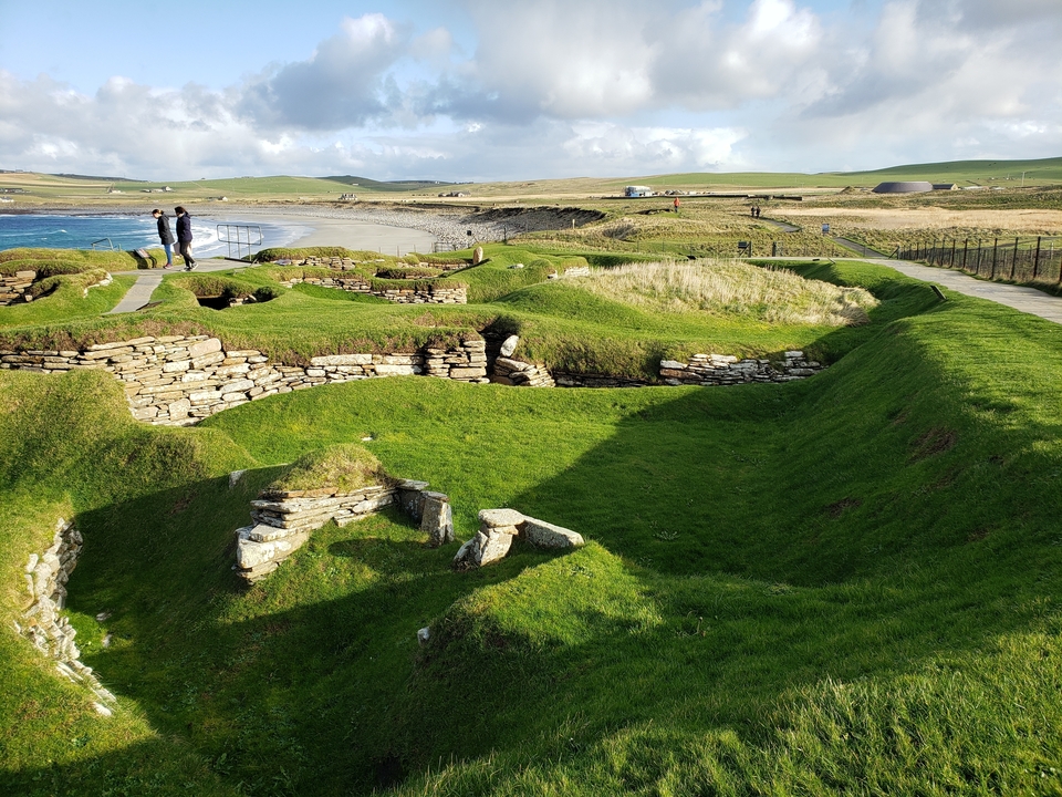 Ruines couvertes d'herbe au bord de la mer avec des visiteurs