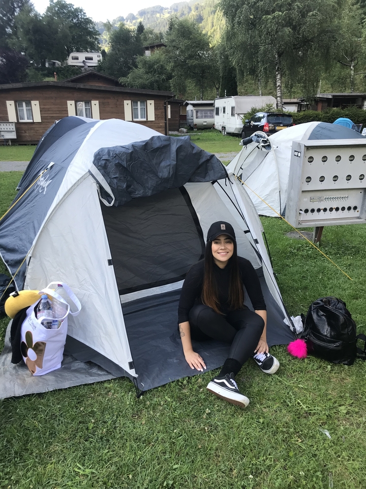 Une personne assise devant une tente de camping.