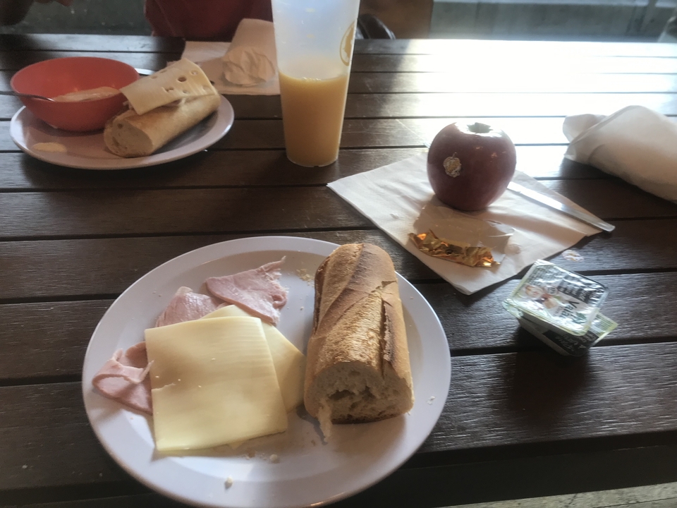 Un petit-déjeuner artistique composé de jambon, fromage, baguette et jus.