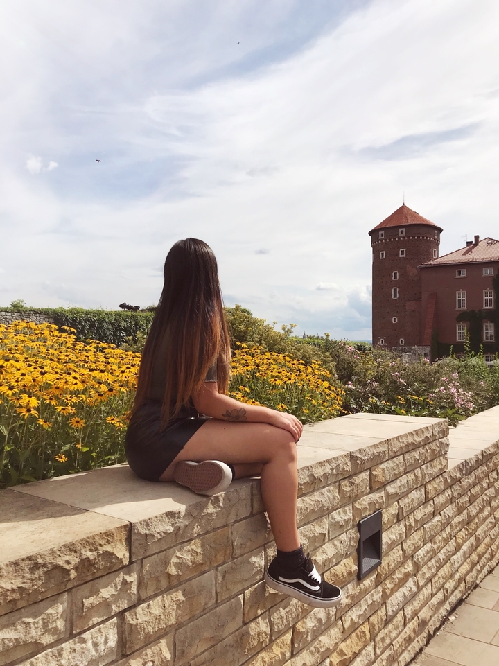 Une personne assise près de fleurs avec une tour en arrière-plan.