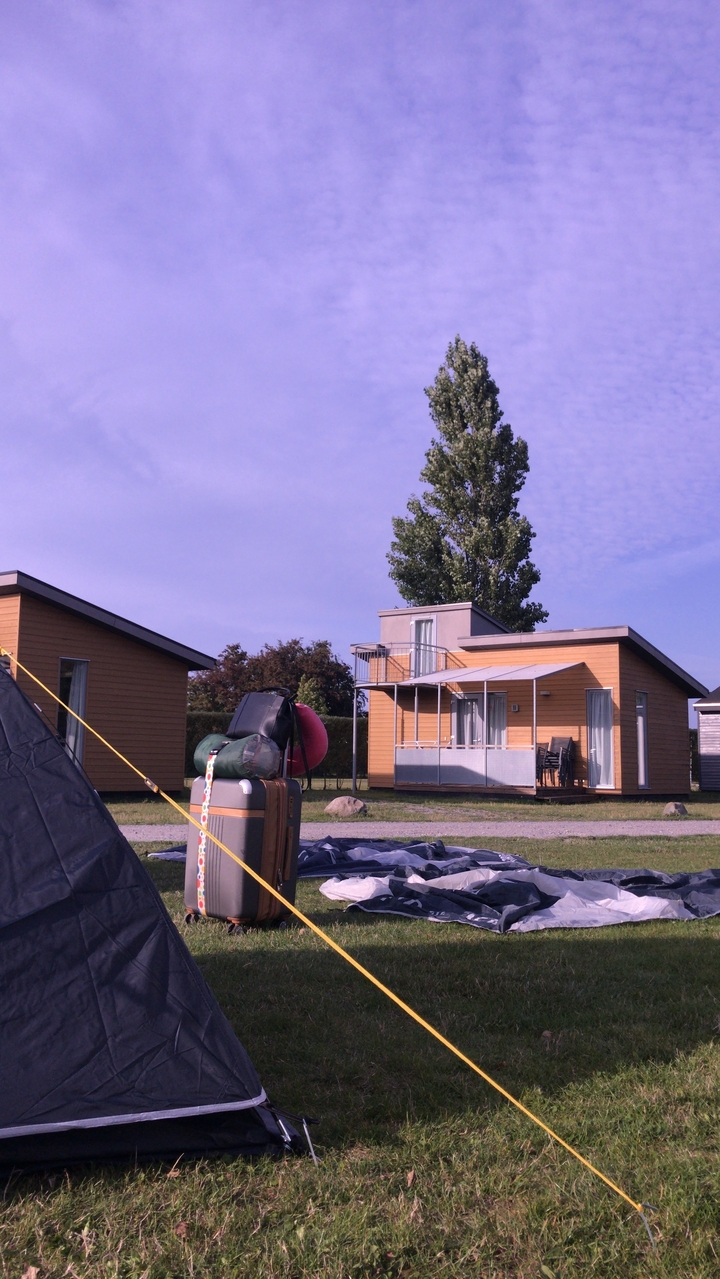 Une petite cabane de camping dans un cadre de camping avec des bagages à l'extérieur.