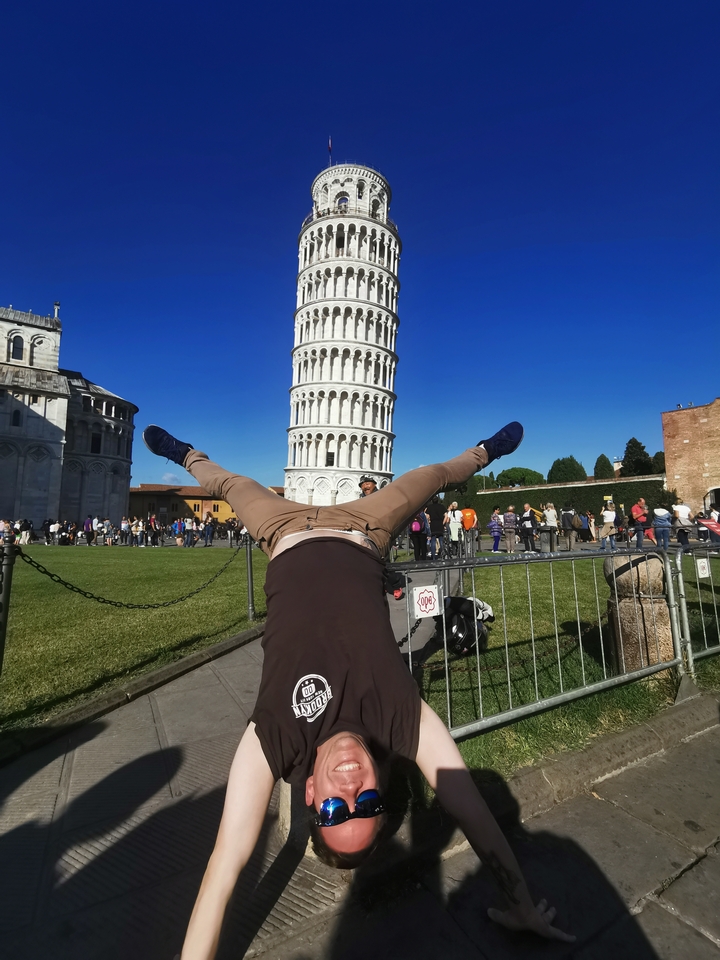 Homme posant devant la tour penchée de Pise.