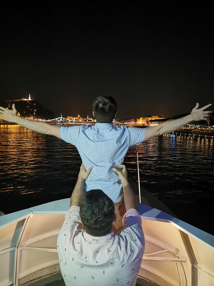 Homme profitant d'une vue nocturne depuis un bateau avec les lumières de la ville en arrière-plan.
