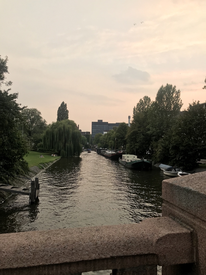 Un canal bordé d'arbres et de bateaux amarrés au coucher du soleil.