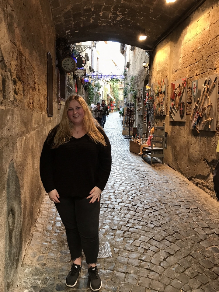 Personne qui pose dans une ruelle pavée.