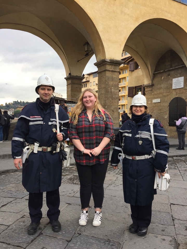 Trois personnes posant en uniforme sur une place de ville.