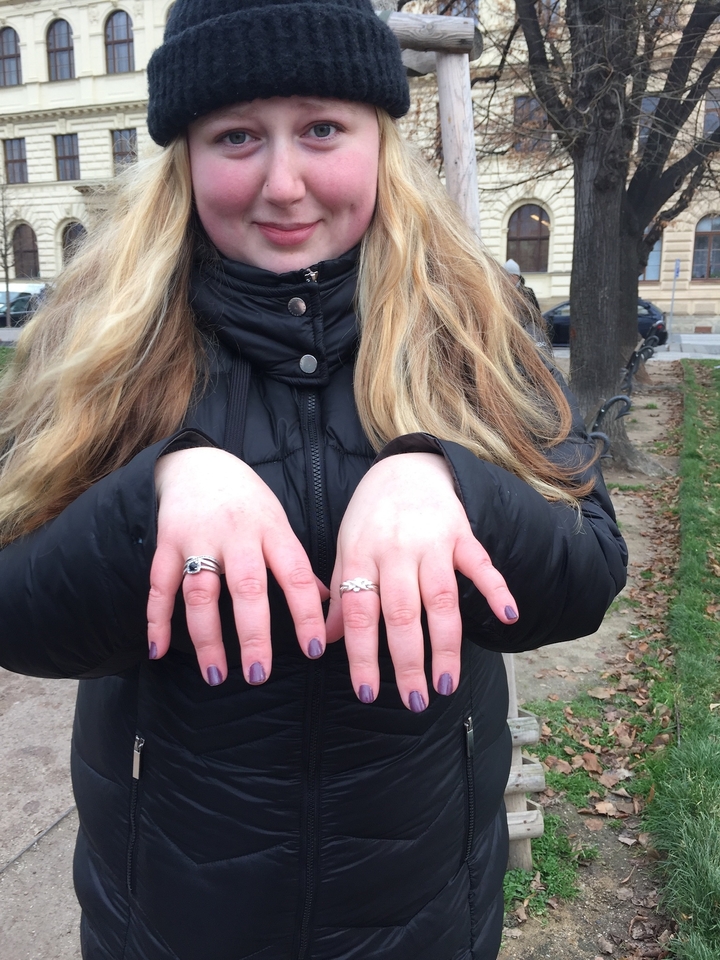 Des mains portant des bagues sur une veste noire.