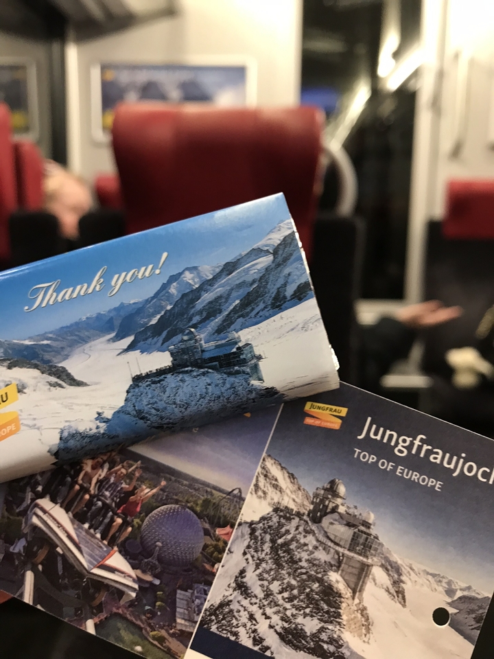 Main tenant une barre de chocolat avec un emballage représentant des montagnes enneigées.