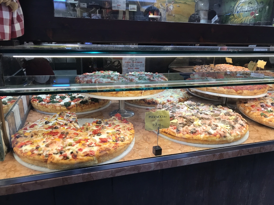 Des pizzas assorties dans une vitrine d'exposition.