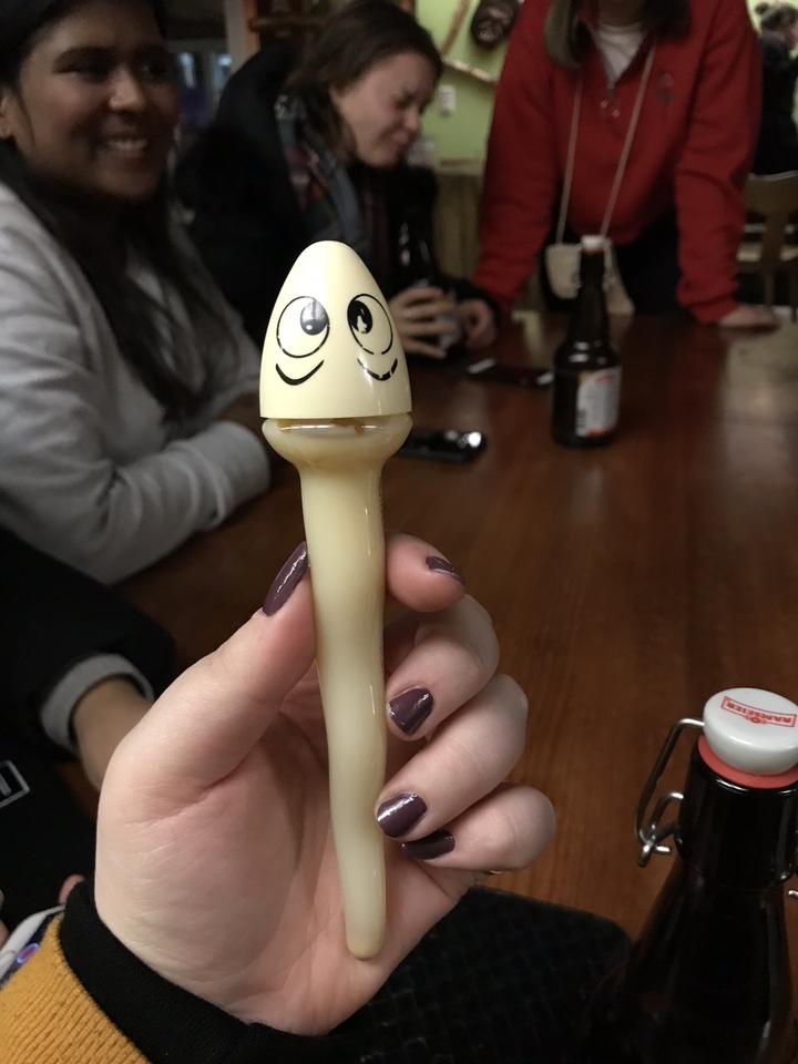 Une main tenant un petit jouet ou souvenir avec un visage peint dessus.