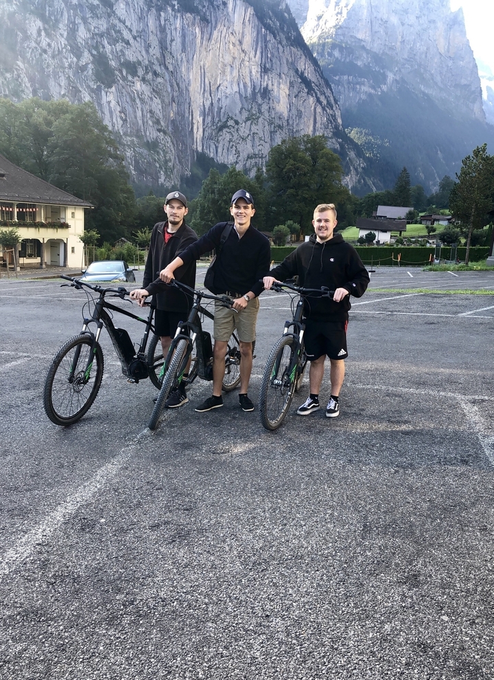 Trois personnes avec des vélos dans un parking.