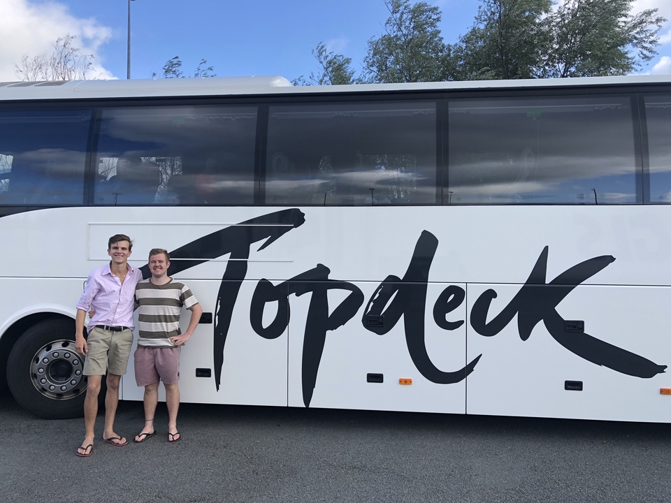 Des gens debout devant un autocar de tourisme Topdeck.
