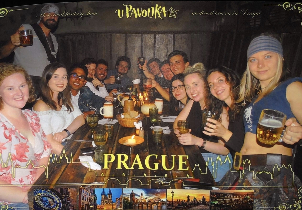 Photo de groupe dans un pub avec superposition de texte 'Prague'.
