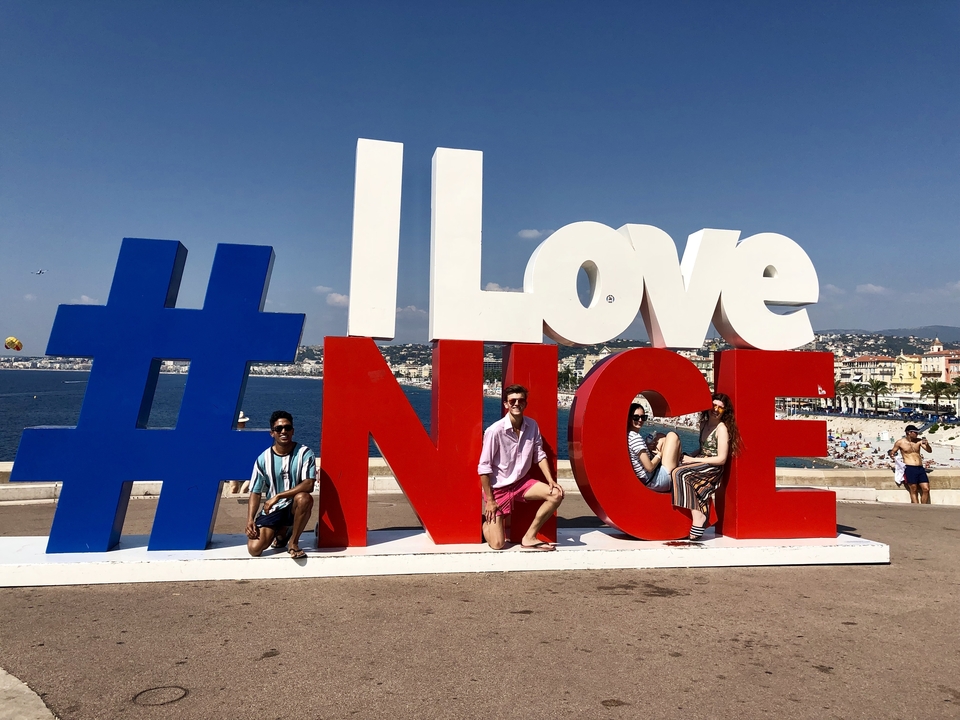 Des gens qui posent avec un panneau « J'aime Nice ».