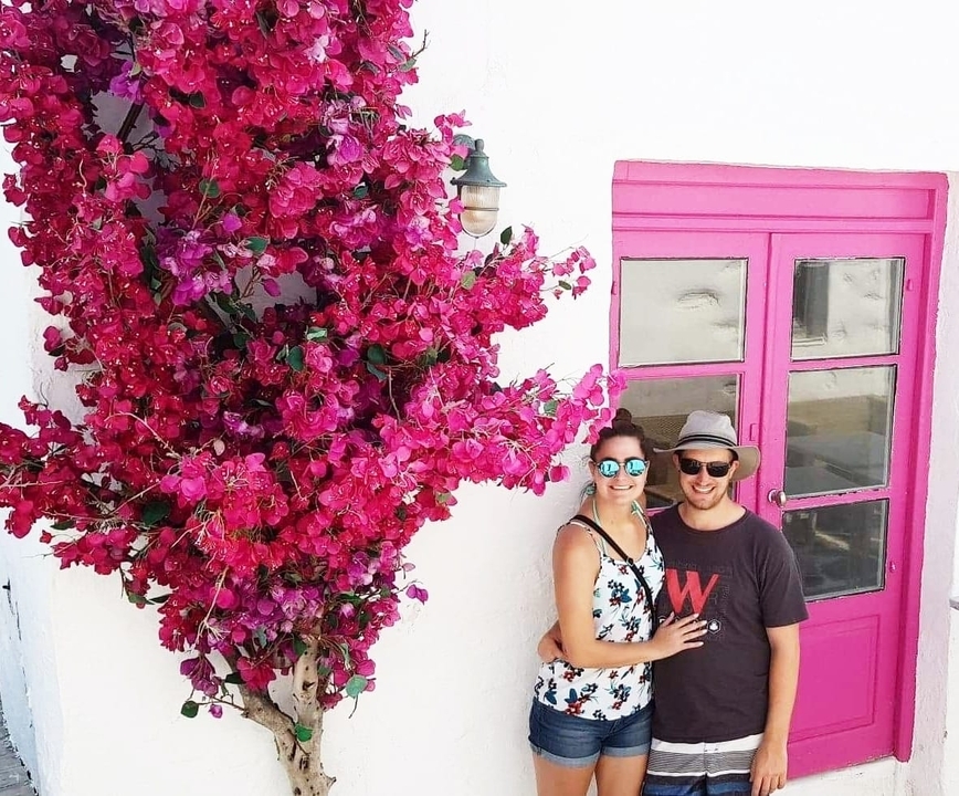 Un couple debout devant un bougainvillier rose vif.