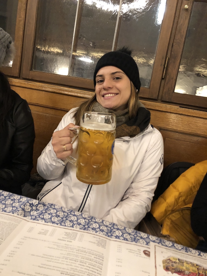 Une personne tenant une grande chope de bière, souriante.