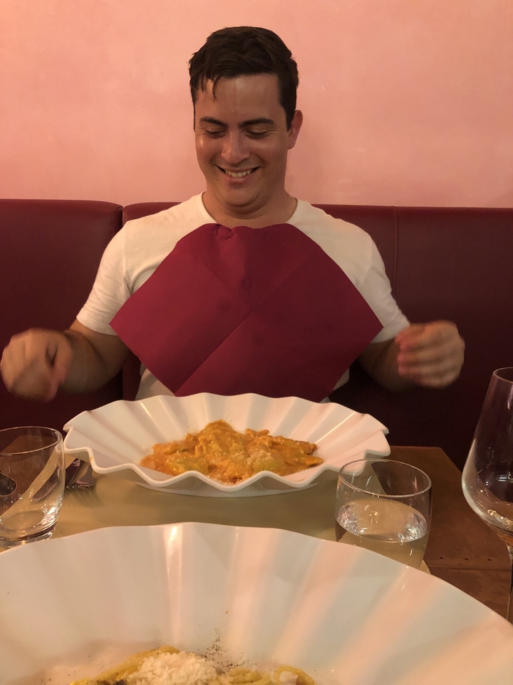 Une personne dans un restaurant mangeant des pâtes, portant une serviette en guise de bavoir.