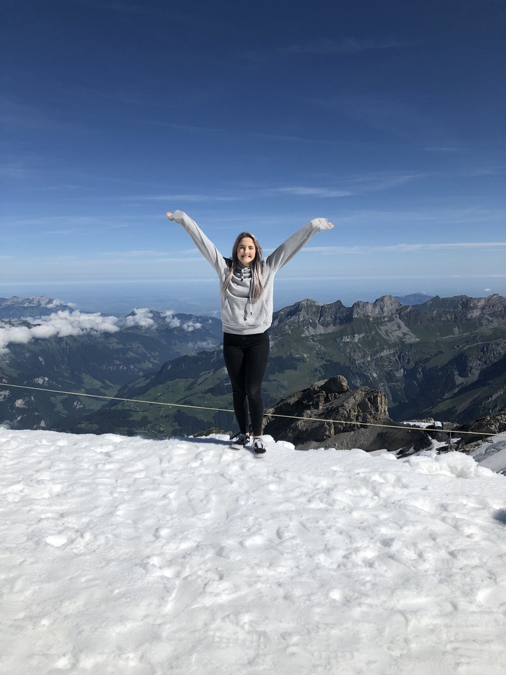 A person with arms raised in a scenic snowy mountainous area.