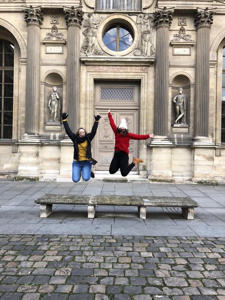 Deux personnes sautant de joie devant un bâtiment historique.