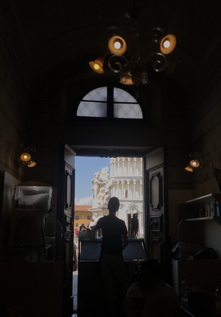 Vue intérieure encadrant une sculpture et la Tour penchée de Pise.