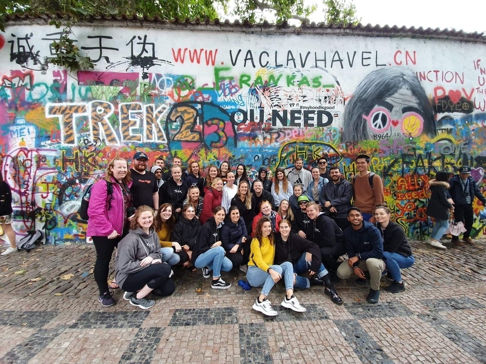 Groupe debout devant un mur de graffitis coloré.
