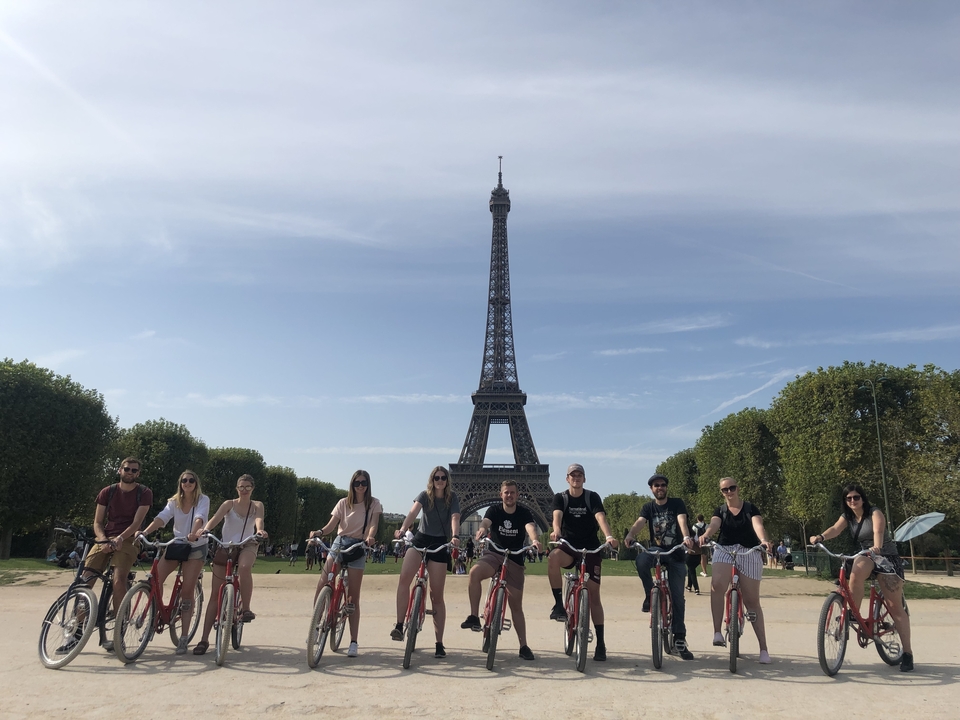 Groupe de cyclistes posant devant une tour de fer emblématique.