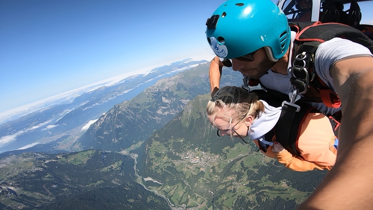 Saut en parachute en tandem avec un vaste paysage montagneux en contrebas.