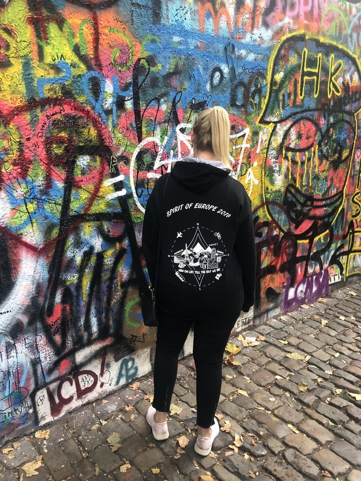 Personne debout devant un mur de graffitis colorés.