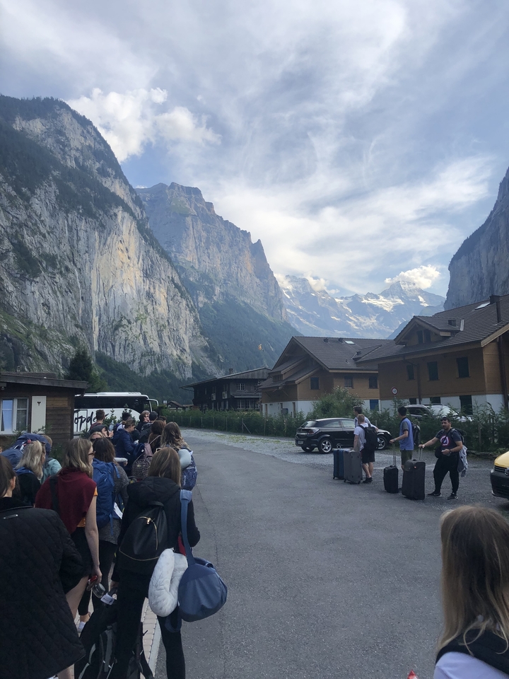 Groupe de personnes avec des bagages près d'un paysage de montagne pittoresque.