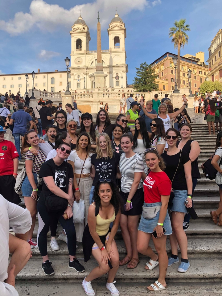 "Groupe de personnes posant sur les marches espagnoles."
Note: "Les marches espagnoles" refers to the famous Spanish Steps (Scalinata di Trinità dei Monti) in Rome. In French, they are sometimes also called "l'escalier de la Trinité-des-Monts."