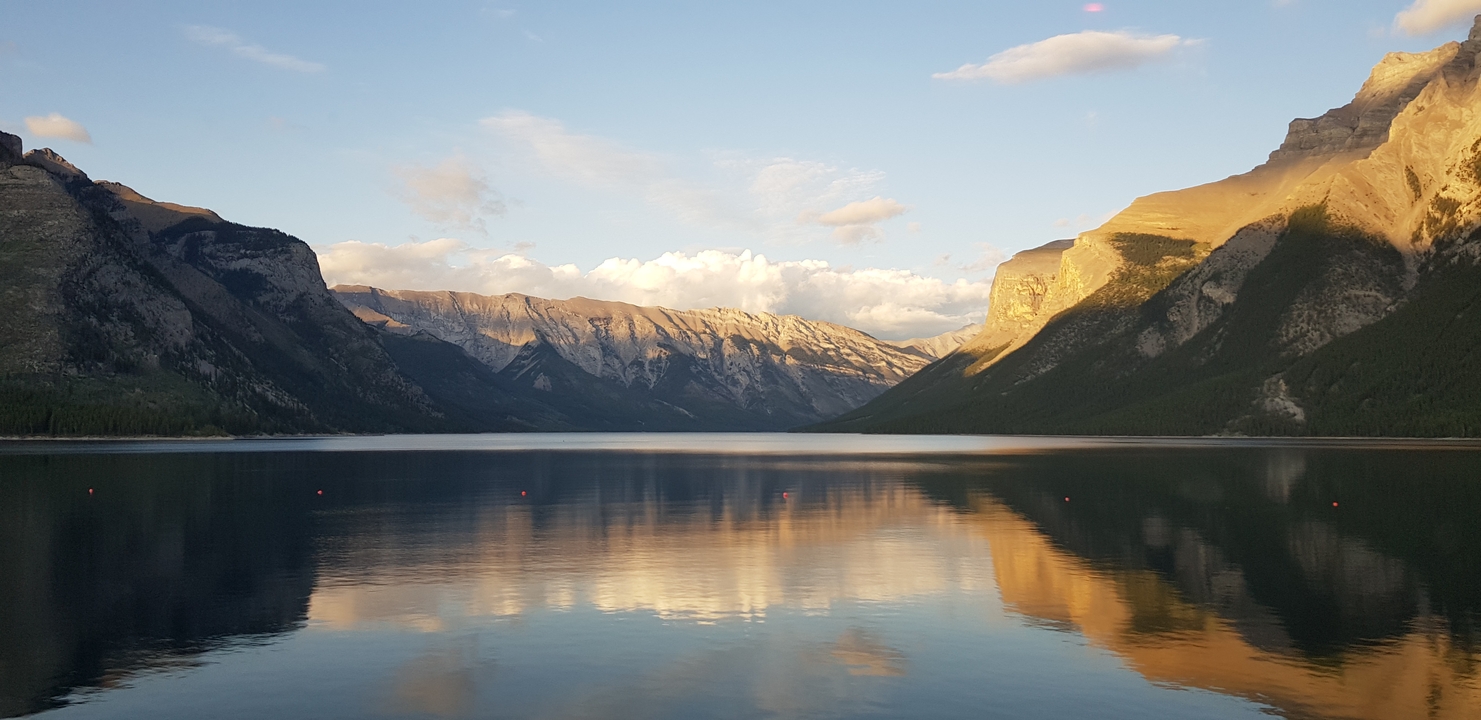 Lac avec des montagnes en arrière-plan au coucher du soleil.