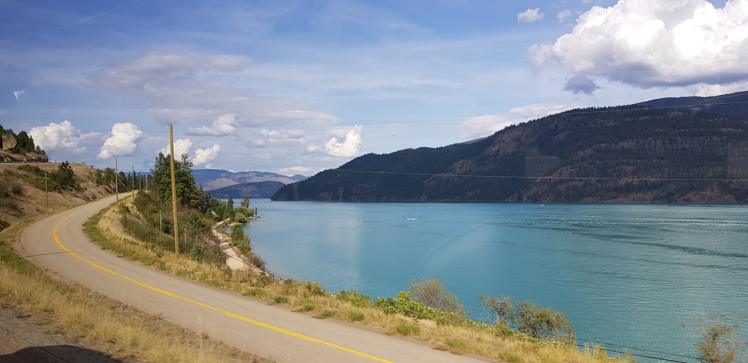 Route longeant une rivière avec des collines en arrière-plan.
