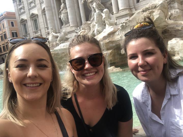 Three friends posing in front of a famous fountain.
