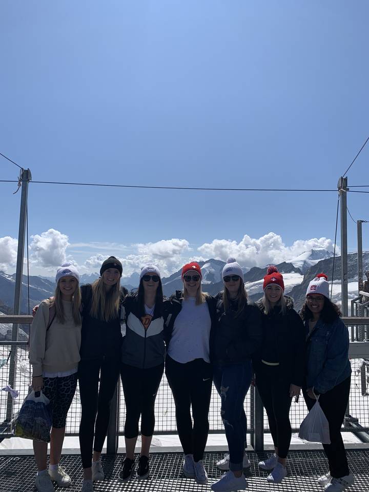 Group of people smiling with snow-capped mountains in the background.
