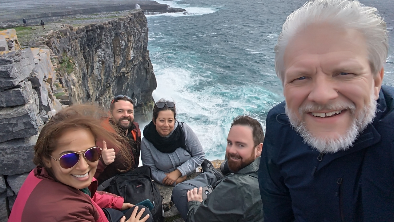 Groupe de personnes posant près d'une falaise surplombant la mer.