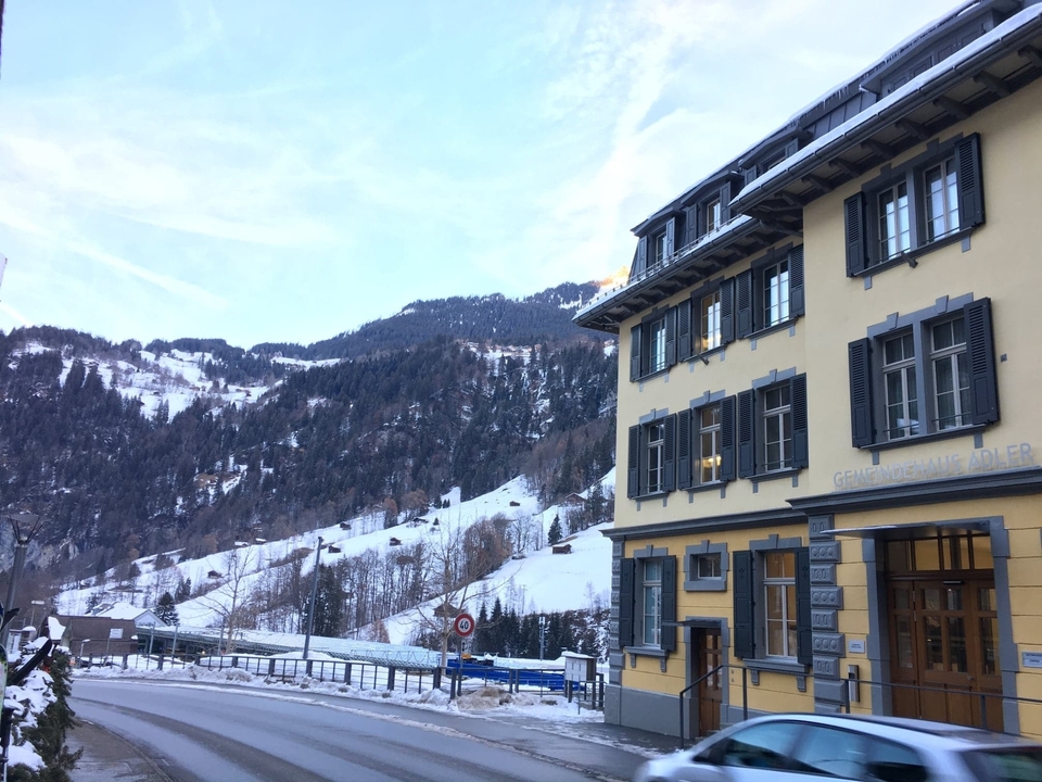 Traditional alpine building with snow-laden mountain background.