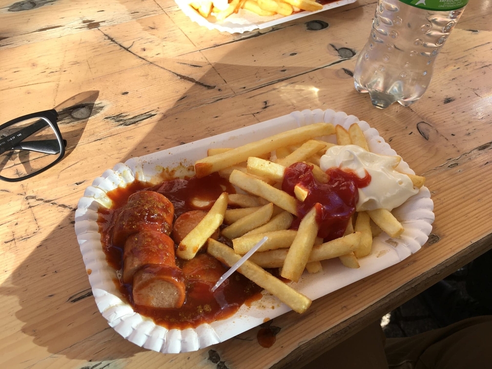 Assiette de currywurst avec frites et ketchup sur une table en bois.