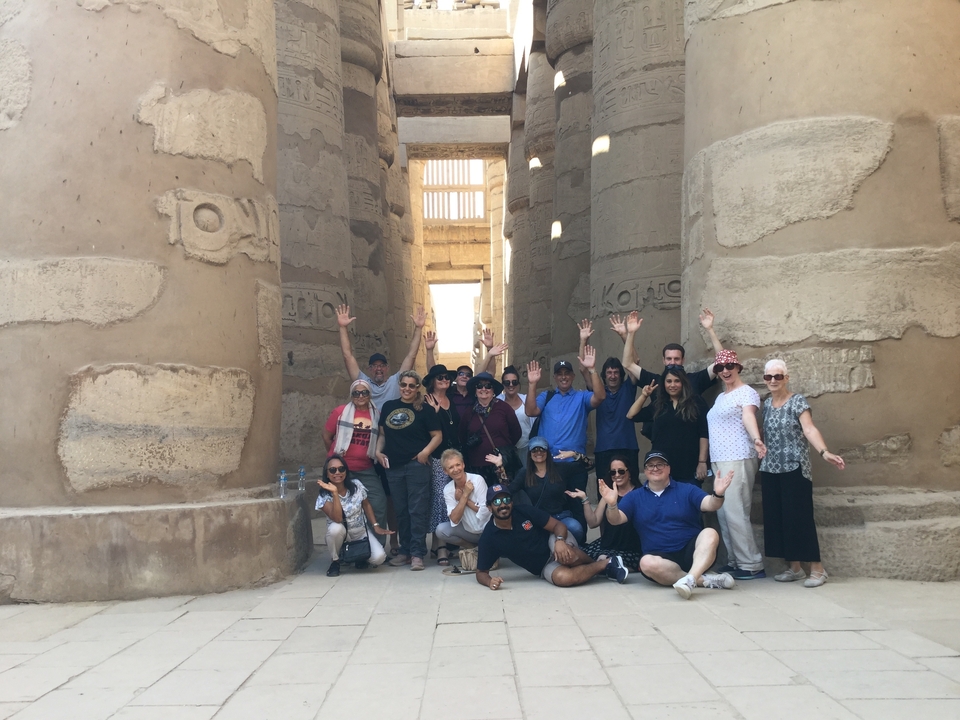 Groupe de touristes posant entre des colonnes anciennes dans un temple.