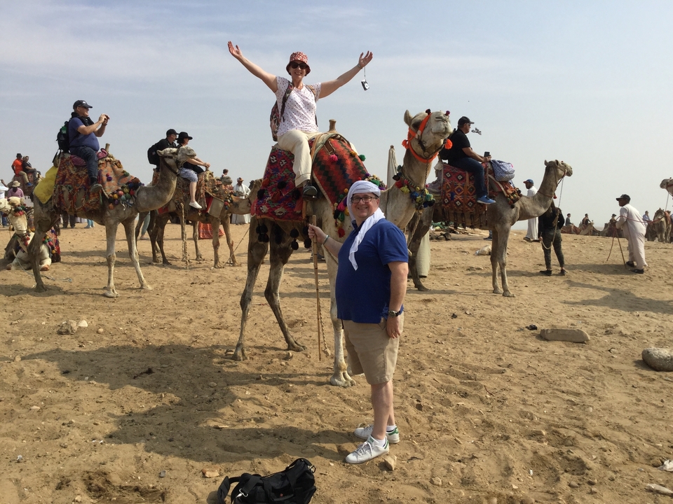 Des gens qui montent des chameaux dans un désert avec un ciel dégagé.