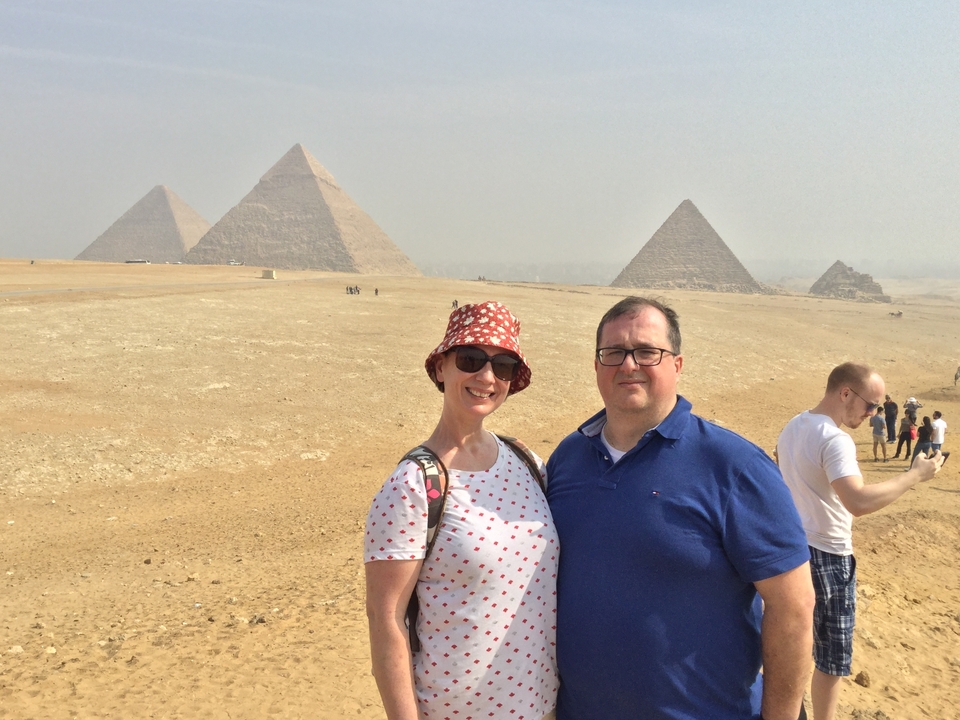 Deux personnes avec des pyramides en arrière-plan, par une journée ensoleillée.