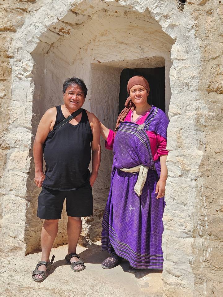 Two people standing at the entrance of a white stone cave.