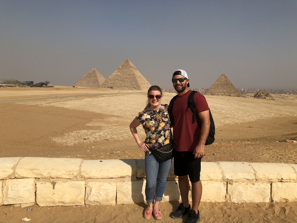 Des touristes posant devant des pyramides par une journée ensoleillée.