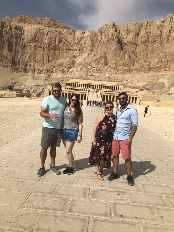 Groupe de personnes debout devant le temple funéraire d'Hatchepsout.