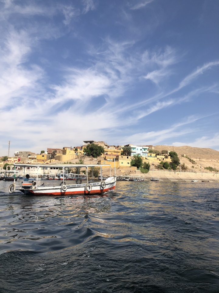 Une scène de rivière avec des maisons colorées sur une colline.